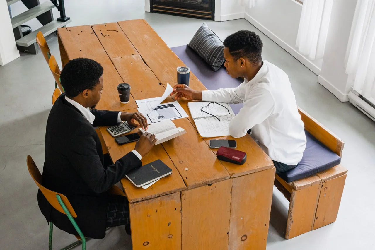 Two business professionals discussing paperwork at a table. Illustrative stock photograph.